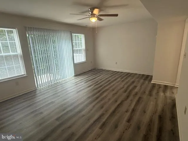 an empty room with wooden floor fan and windows