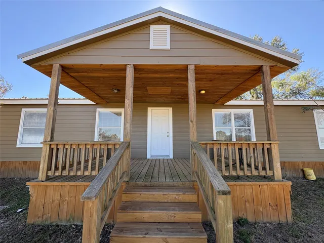 a view of a house with wooden deck and furniture