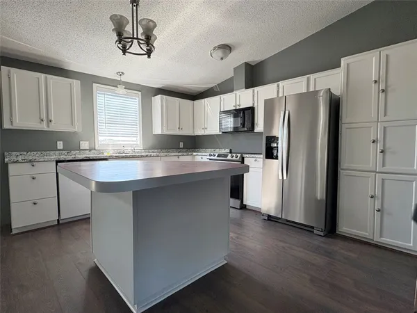 a kitchen with stainless steel appliances a refrigerator a sink dishwasher a stove and white cabinets with wooden floor