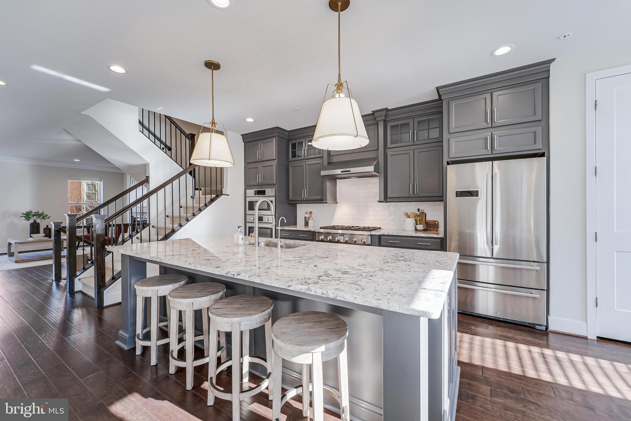 11695 Sunrise Square Place Reston, VA 20191 - Photo 27 of 72 a kitchen with stainless steel appliances kitchen island a refrigerator and wooden floor