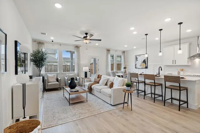 a living room with furniture kitchen view and a large window