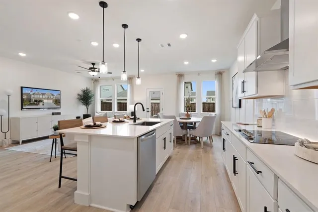 a large kitchen with lots of counter space a sink appliances and a living room view