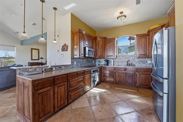 a large kitchen with a large counter top a sink a counter space and cabinets