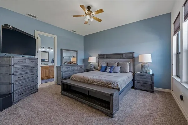a spacious bedroom with a bed and a flat screen television