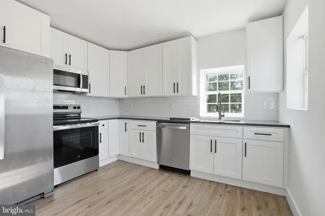 a kitchen with granite countertop white cabinets and stainless steel appliances