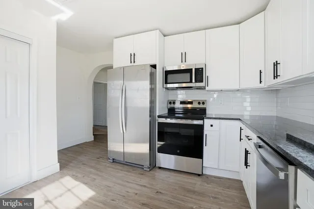 a kitchen with cabinets stainless steel appliances and wooden floor