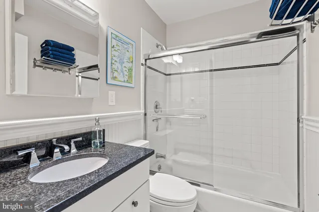a bathroom with a granite countertop sink toilet a mirror a vanity and shower