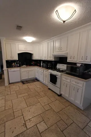 a kitchen with granite countertop a sink a stove top oven and cabinets