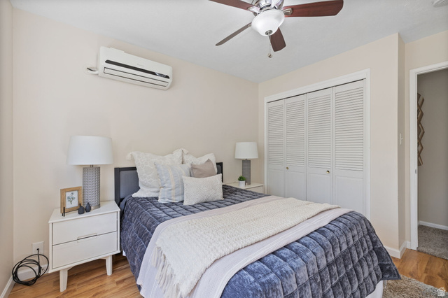2370 Quail Run Circle East Sandy, UT 84093 - Photo 20 of 54 Bedroom featuring wood-finish flooring, a wall-mounted mini-split air conditioning unit, and a ceiling fan with integrated lighting