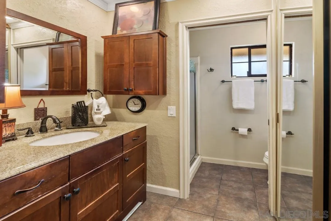 12814 Iola Way Poway, CA 92064 - Photo 22 of 36 a bathroom with a granite countertop sink a mirror and a shower