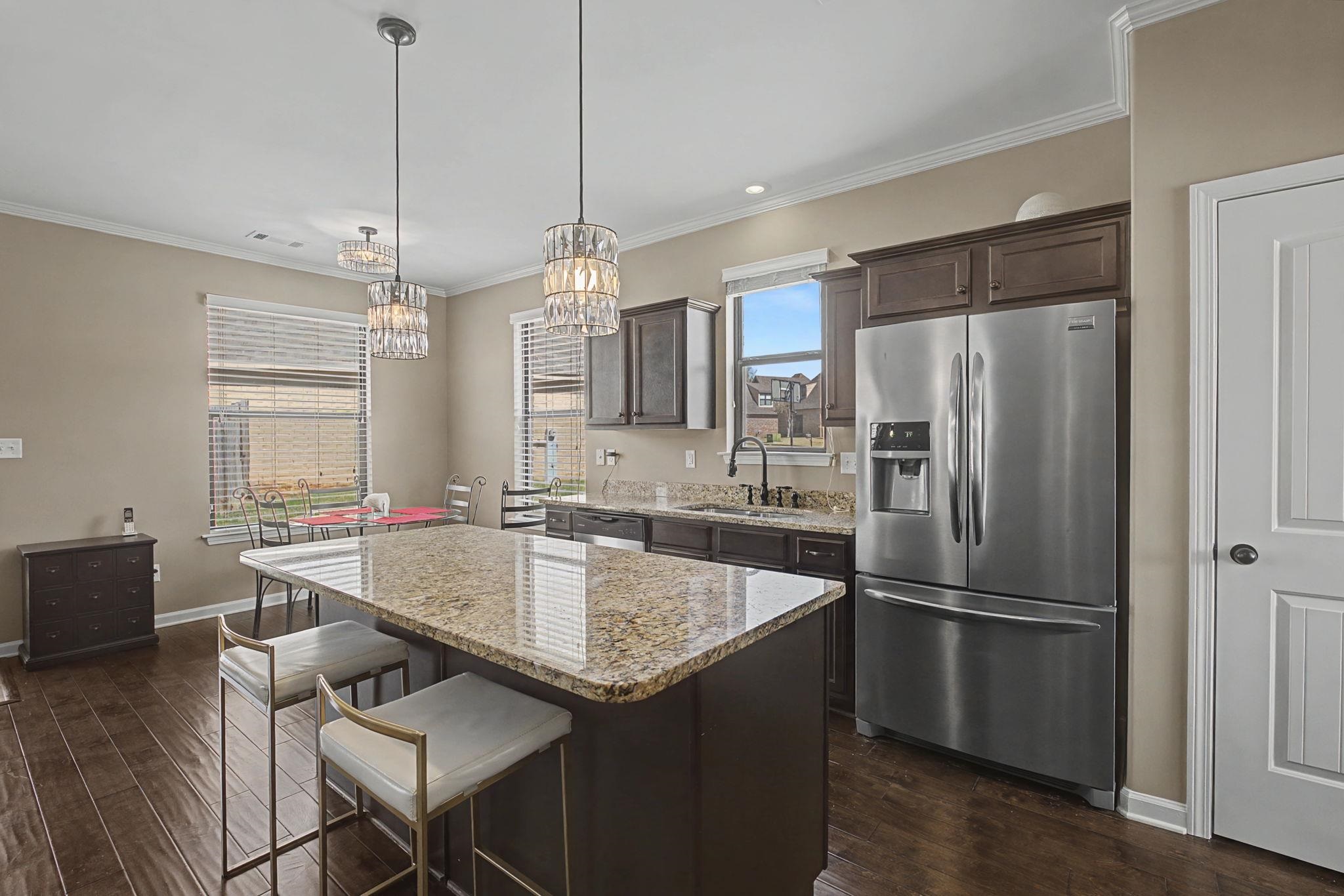 12436 Dusty Field Road Arlington, TN 38002 - Photo 14 of 40 Kitchen with dark wood finish cabinetry, stainless steel appliances, a breakfast bar, a center island, and light stone countertops