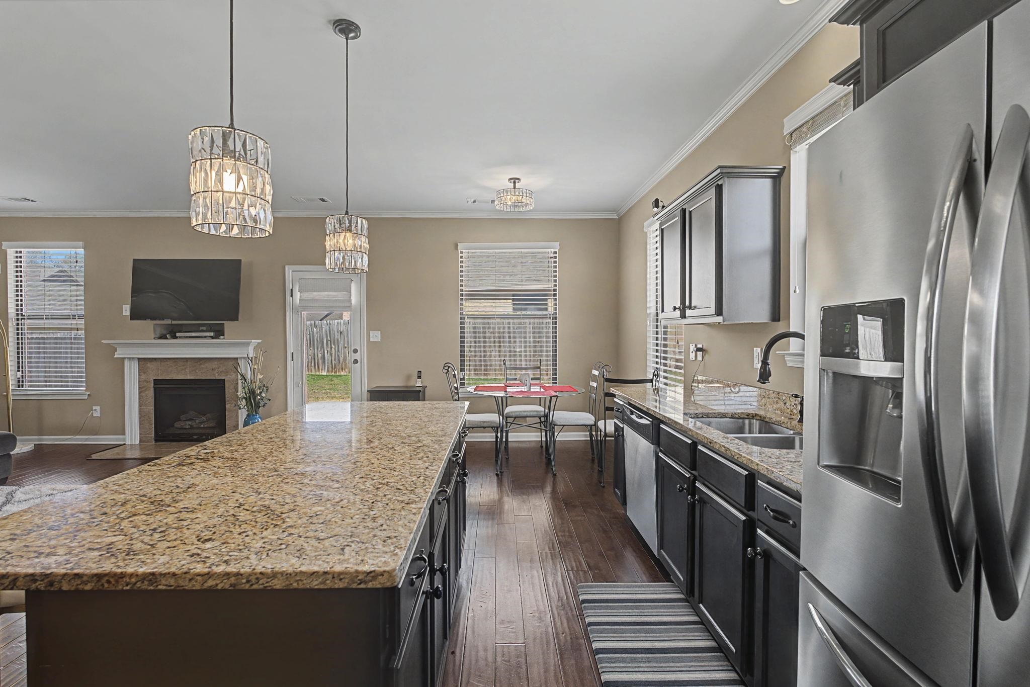 12436 Dusty Field Road Arlington, TN 38002 - Photo 40 of 40 Kitchen featuring stainless steel appliances, light stone countertops, dark wood-style floors, open floor plan, and crown molding