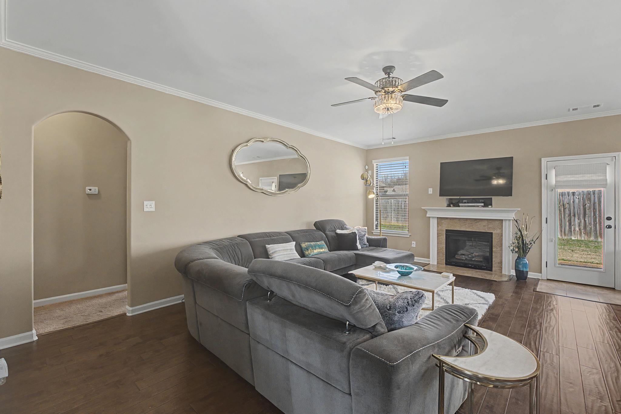 12436 Dusty Field Road Arlington, TN 38002 - Photo 8 of 40 Living room featuring arched walkways, dark wood-style floors, ceiling fan, a fireplace, and ornamental molding