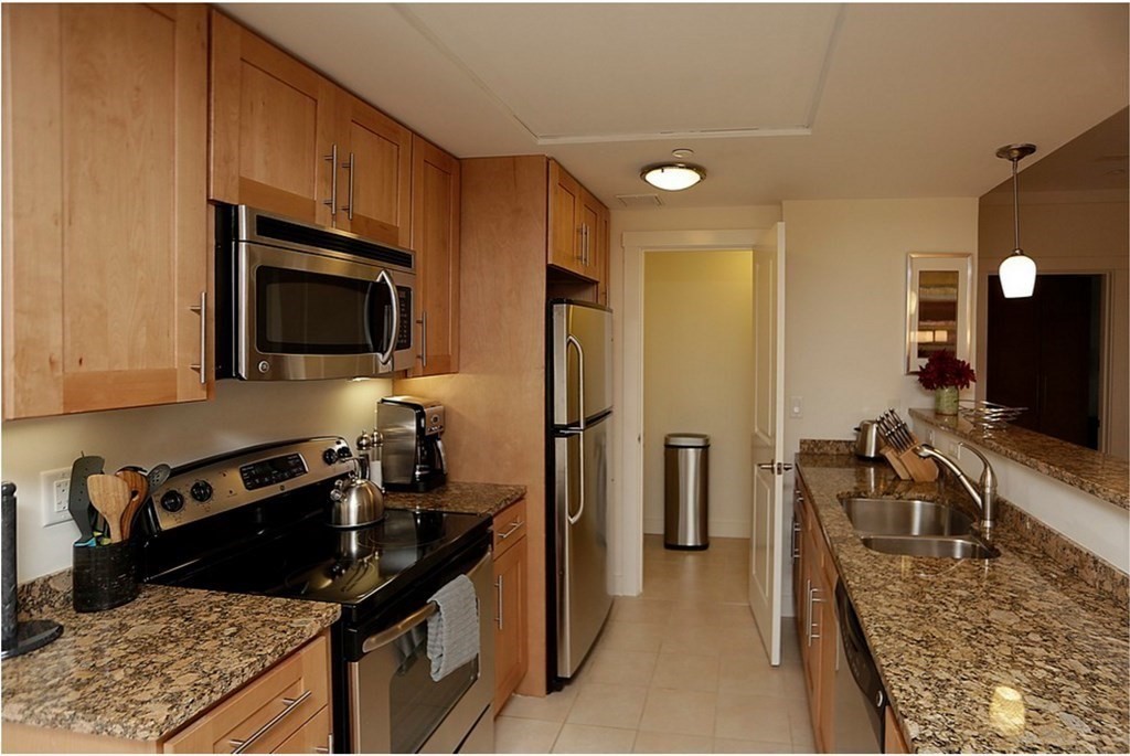 a kitchen with granite countertop a refrigerator stove and sink