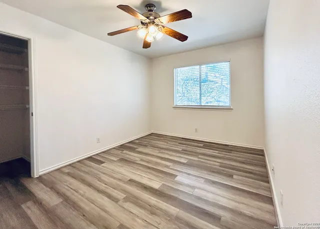 an empty room with wooden floor and windows