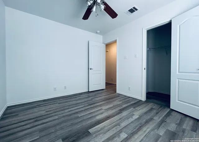 a view of empty room with wooden floor and fan