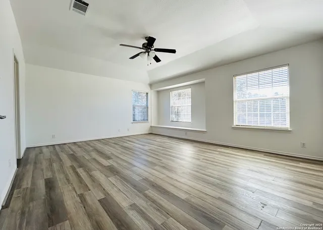 a view of empty room with wooden floor and ceiling fan