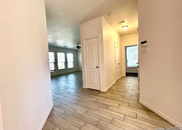 a view of a hallway with wooden floor and a bathroom