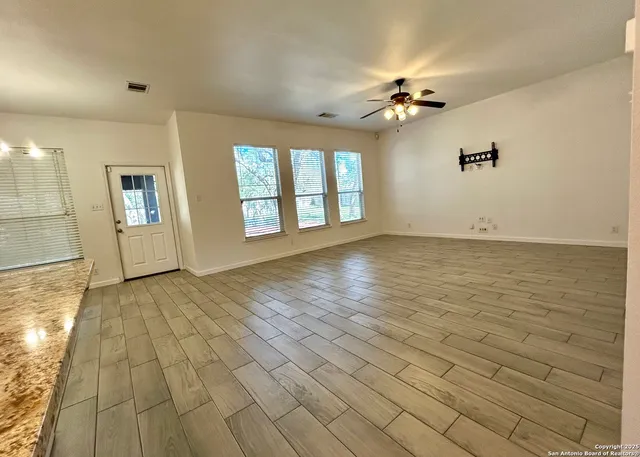 a view of an empty room with window and wooden floor