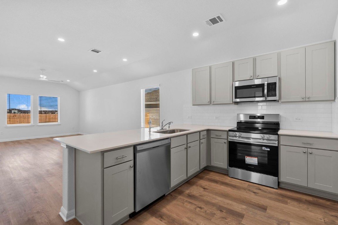 125 Hatari Trail Jarrell, TX 76537 - Photo 4 of 40 a kitchen with stainless steel appliances granite countertop a stove sink and microwave