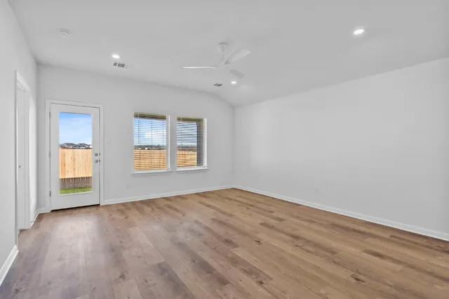 an empty room with wooden floor and windows