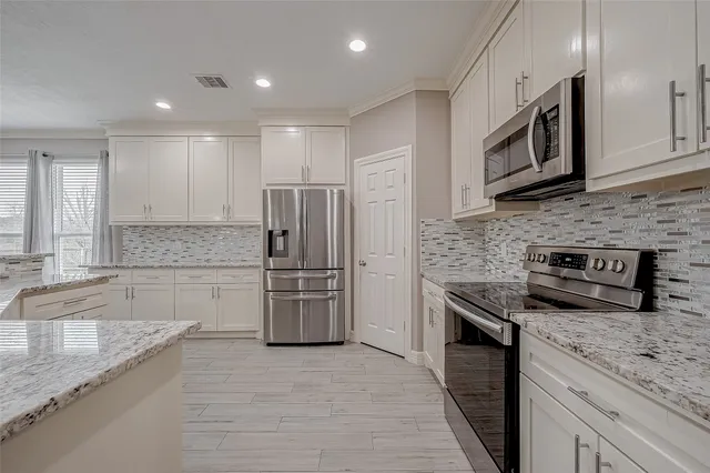 a kitchen with stainless steel appliances granite countertop a refrigerator a stove and a sink