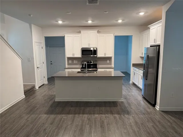 a view of kitchen with stainless steel appliances granite countertop a stove a refrigerator and a sink