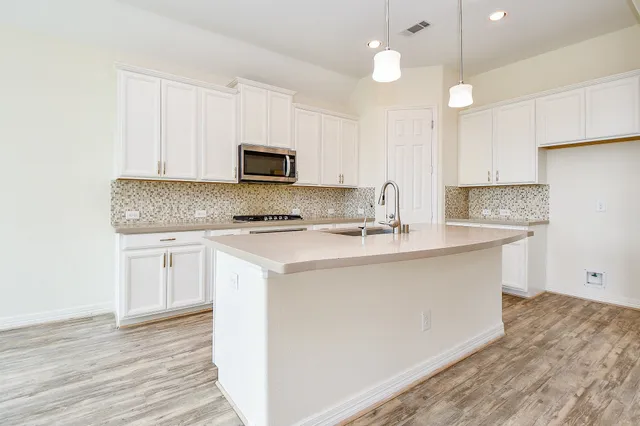 a kitchen with kitchen island a sink stainless steel appliances and cabinets