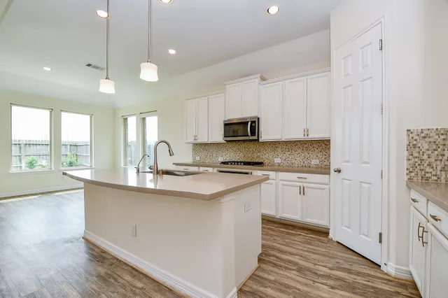 a kitchen with stainless steel appliances granite countertop a sink a stove and a wooden floors
