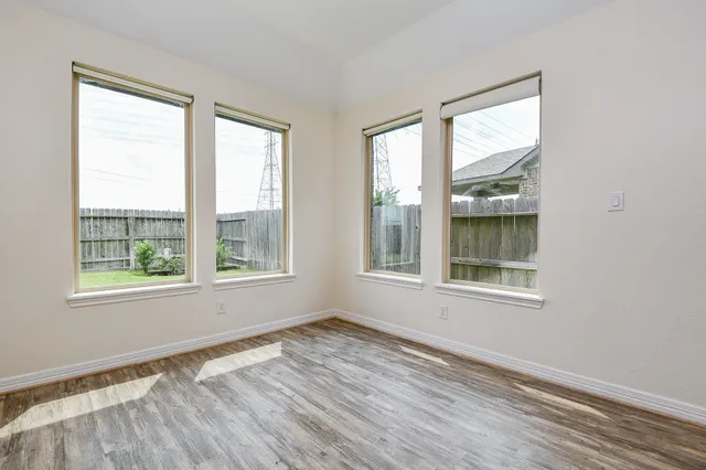 a view of an empty room with wooden floor and a window