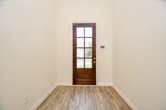 a view of an empty room with wooden floor and fan