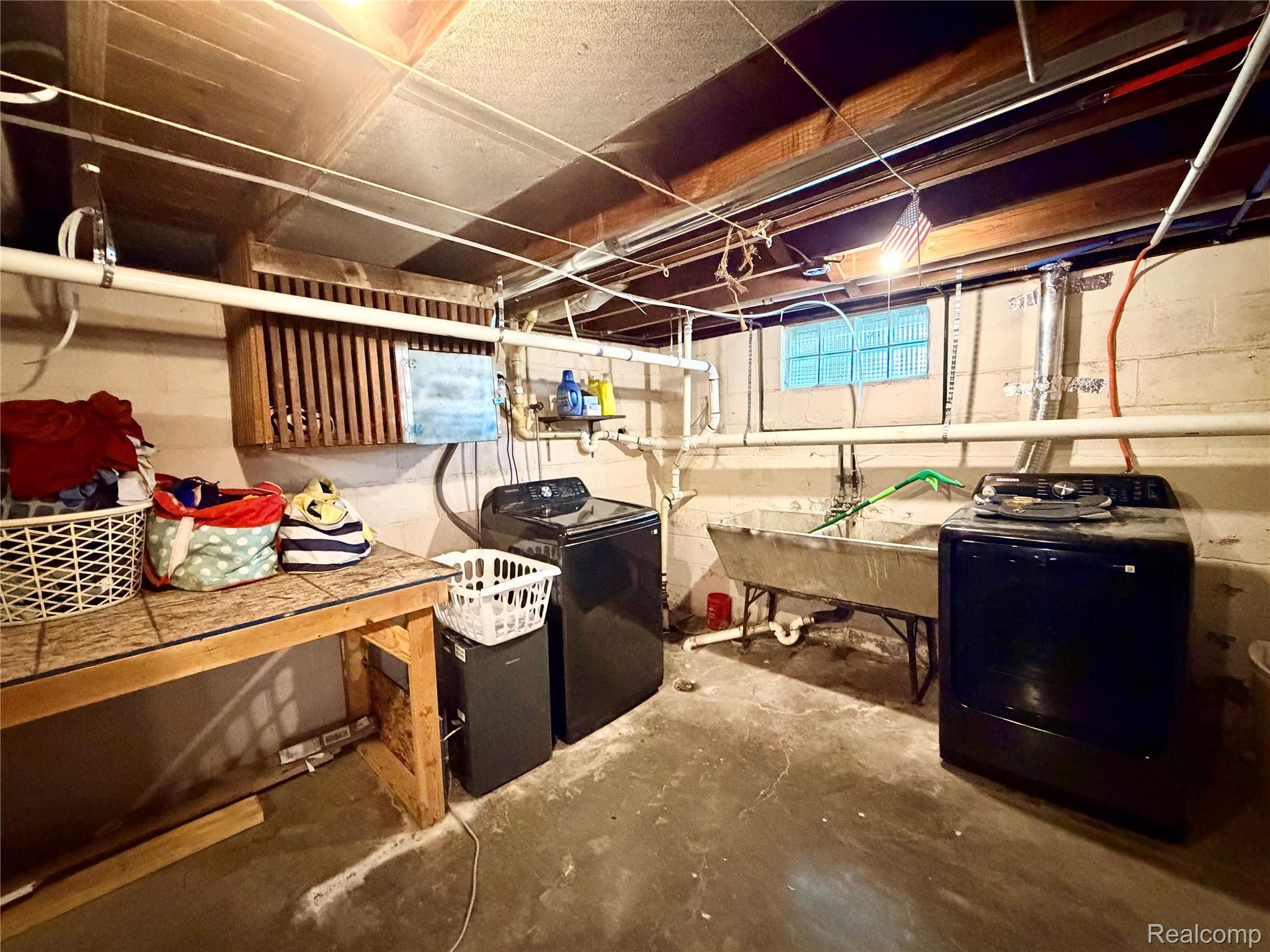 3840 East Dunbar Road Monroe, MI 48161 - Photo 33 of 38 Basement utility area featuring a dual-tub sink, two washing machines, and exposed ceiling joists