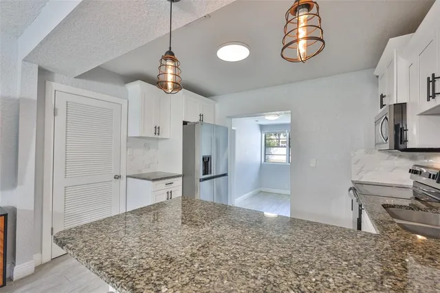 a kitchen with granite countertop white cabinets and stainless steel appliances