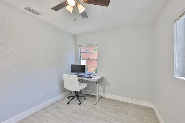 wooden floor in an empty room with a chandelier fan