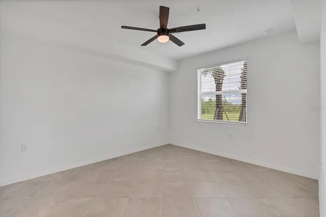 an empty room with window and ceiling fan