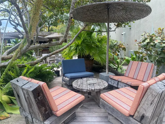 a view of a patio with table and chairs under an umbrella with a barbeque