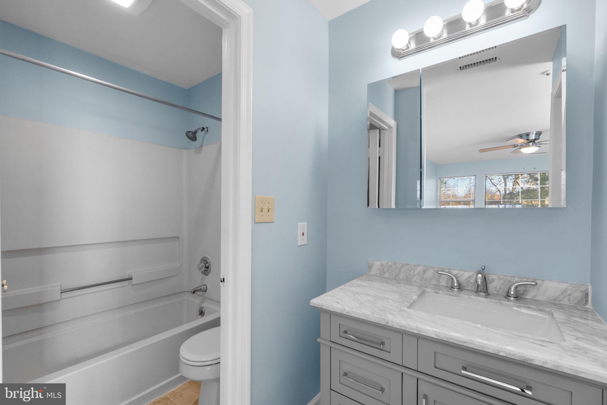 8378 Montgomery Run Road, Unit D Ellicott City, MD 21043 - Photo 27 of 30 a bathroom with a granite countertop sink a toilet and shower