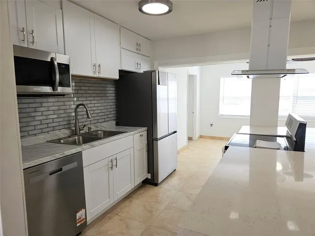 a kitchen with stainless steel appliances a sink a stove a refrigerator a window