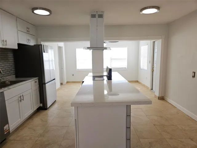 a kitchen with stainless steel appliances a kitchen island hardwood floor sink stove dining table and chairs