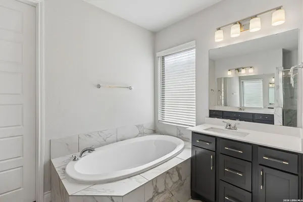 a bathroom with a granite countertop sink a mirror and a bathtub