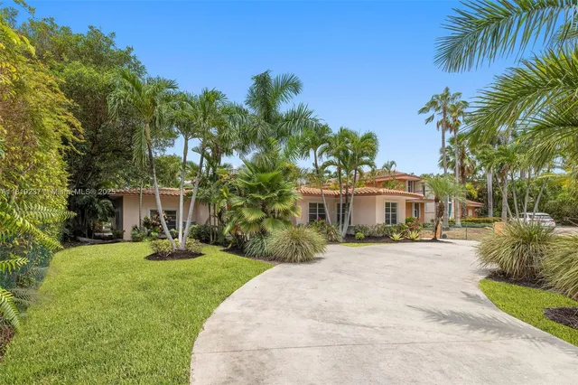 a front view of a house with a yard and palm trees