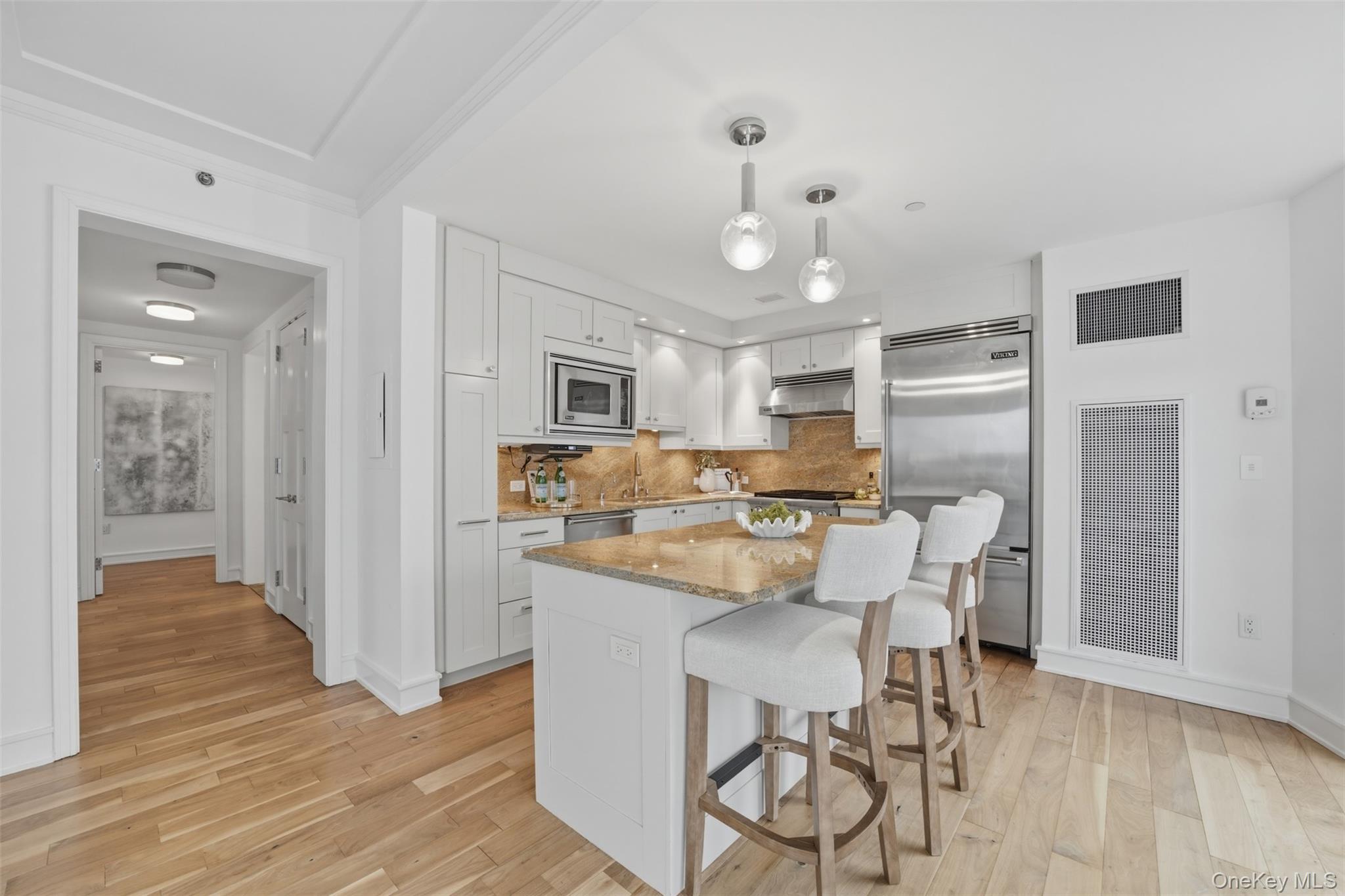 5 Renaissance Square, Unit 16D White Plains, NY 10601 - Photo 3 of 36 a kitchen with stainless steel appliances a dining table chairs refrigerator and sink