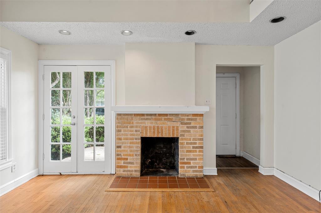 2601 Proctor Avenue Waco, TX 76708 - Photo 4 of 28 an empty room with wooden floor fireplace and windows