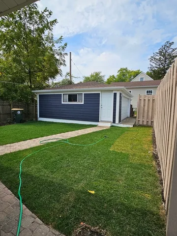 a view of a yard in front of a house with plants and large tree