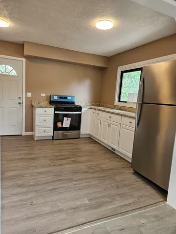 a kitchen with stainless steel appliances granite countertop a refrigerator a stove and a wooden floors