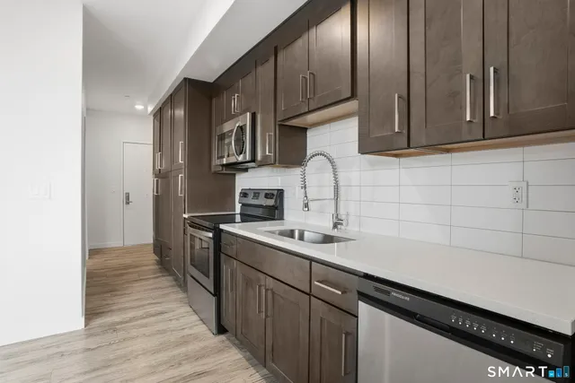 a kitchen with stainless steel appliances a sink dishwasher a stove a refrigerator and cabinets