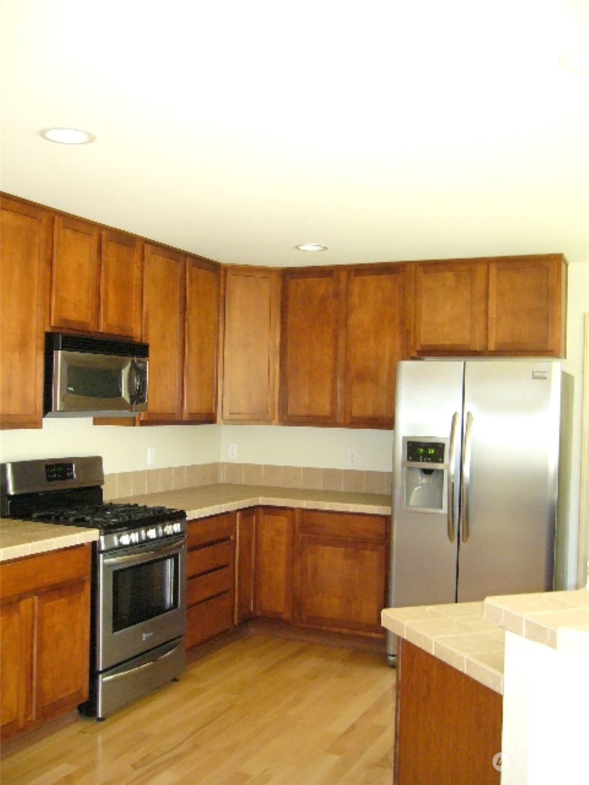 3602 154th Place Southeast Bothell, WA 98012 - Photo 6 of 22 a kitchen with stainless steel appliances a stove a sink and a refrigerator with wooden floor