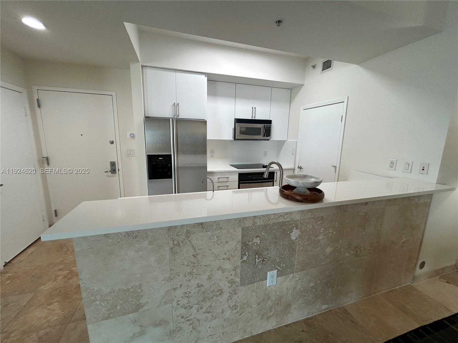 9055 Southwest 73rd Court, Unit 809 Miami, FL 33156 - Photo 16 of 47 a kitchen with kitchen island a counter top space a sink and stainless steel appliances