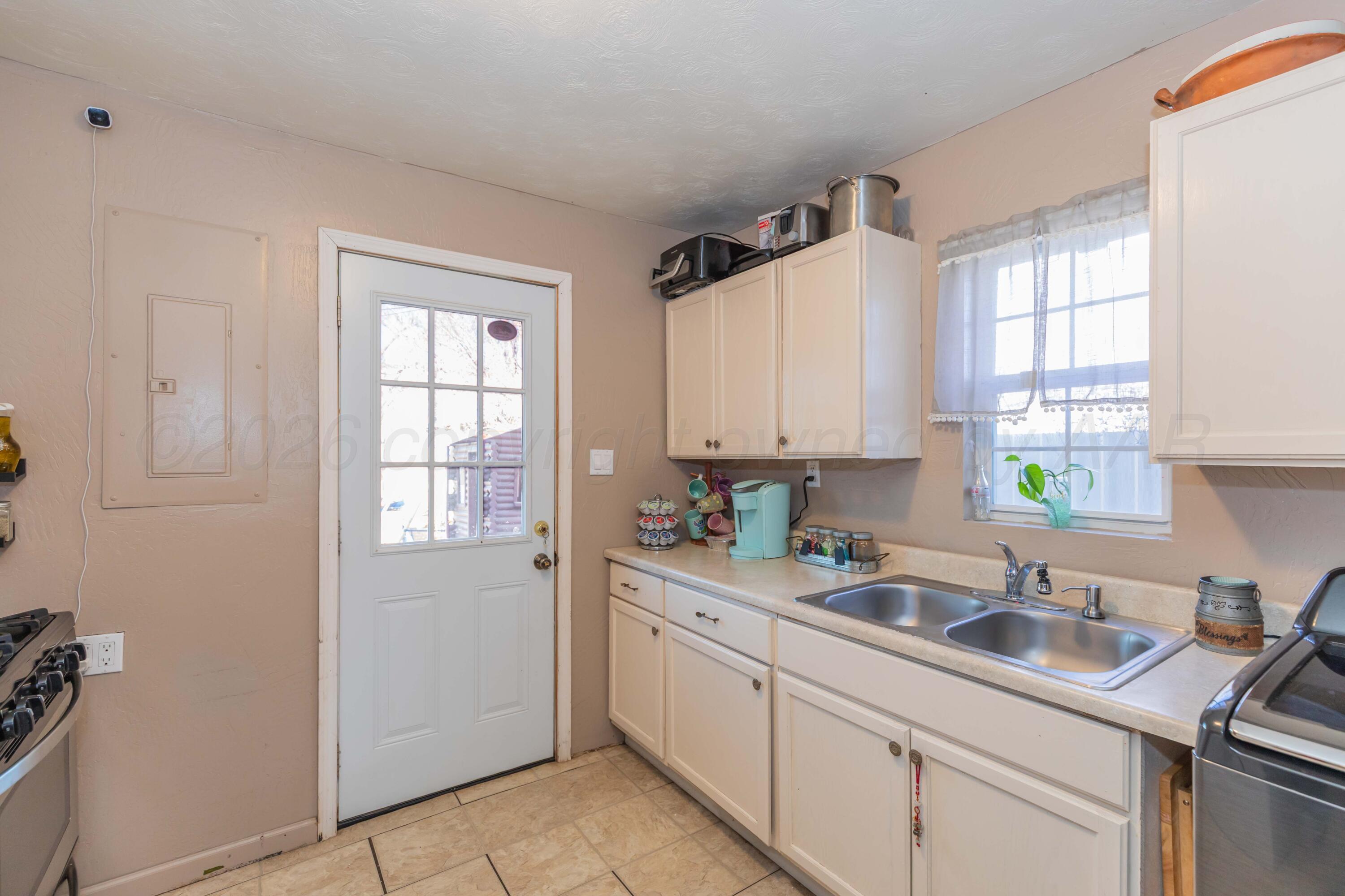 306 Browning Street Amarillo, TX 79104 - Photo 10 of 18 a kitchen with a sink white cabinets and white appliances