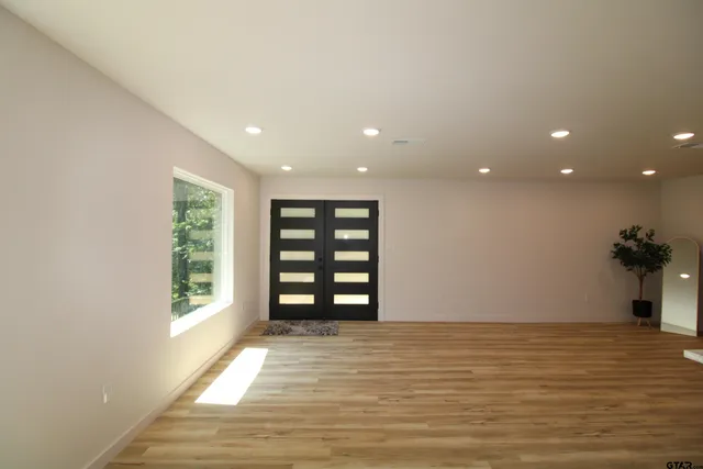 a view of an empty room with wooden floor and a window